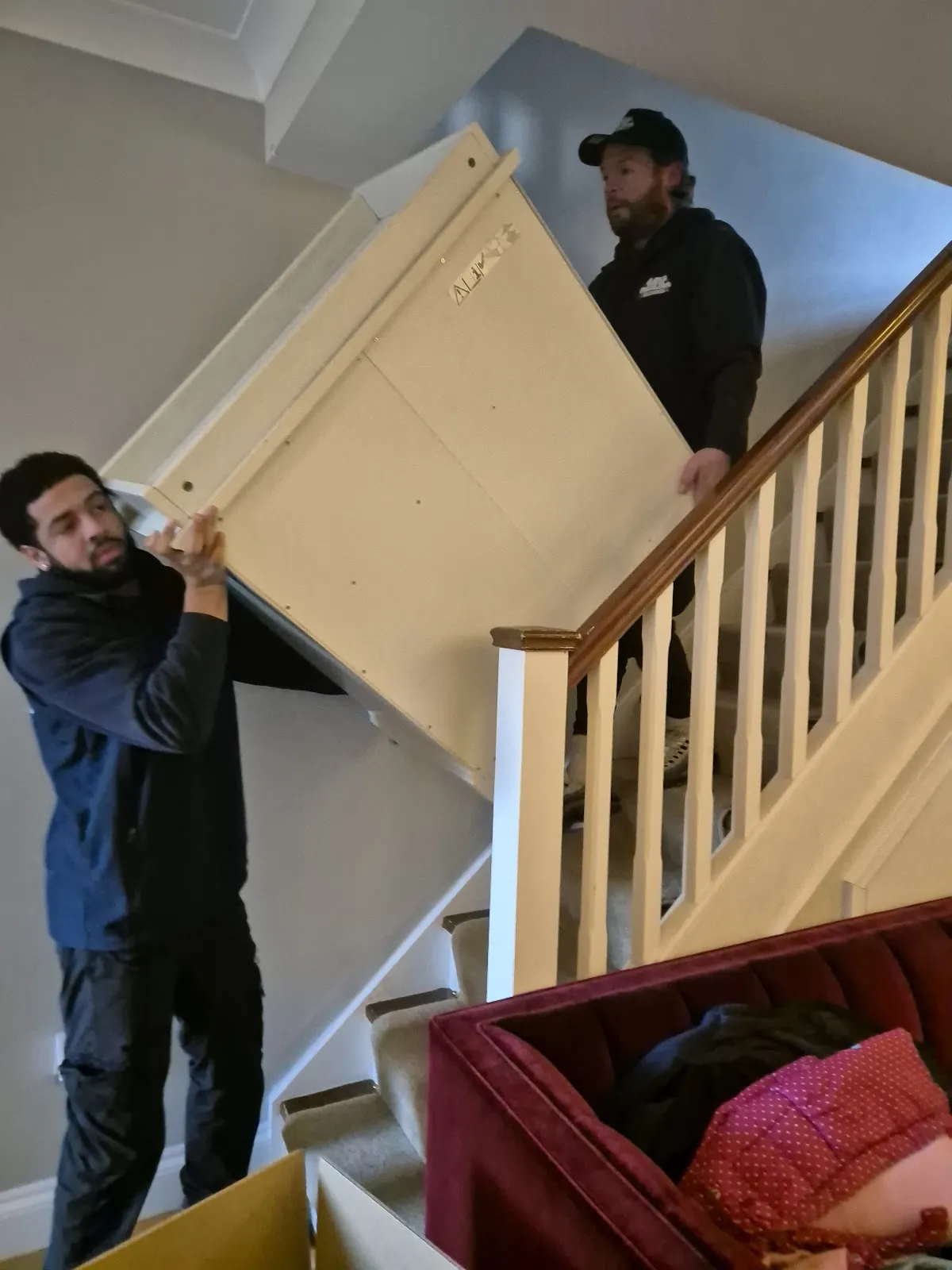 MV Movers crew carrying a wardrobe down the stairs on a house removal